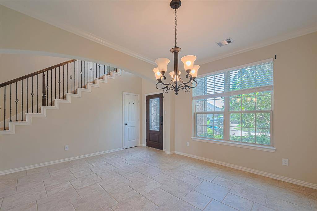 The entryway has the staircase on one side and the formal dining area on the other, all grounded by serene tones and graceful architectural lines.