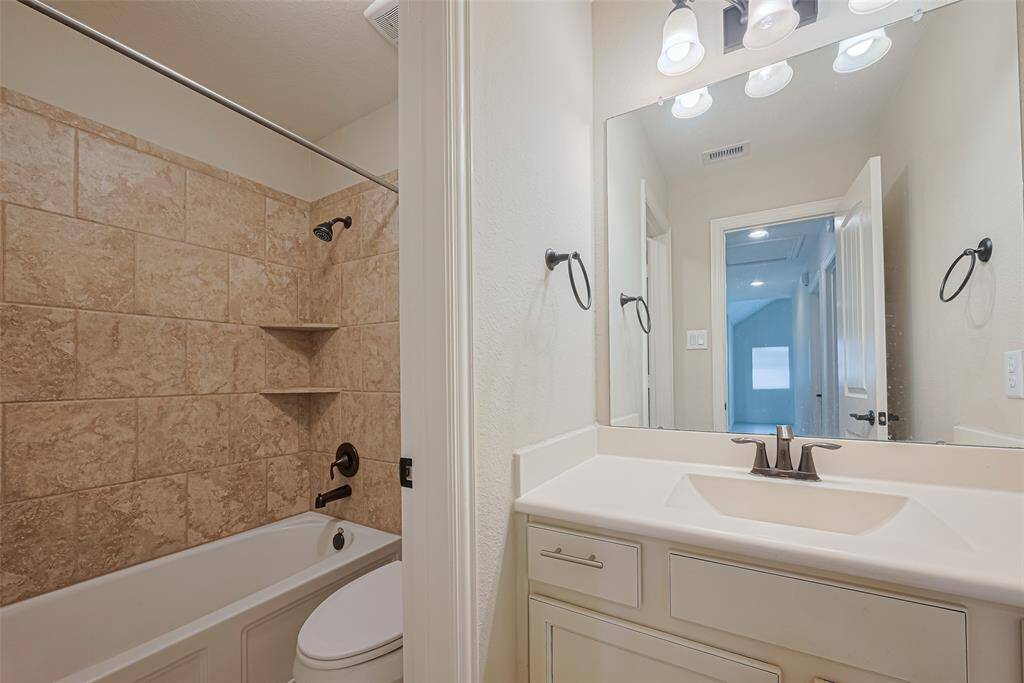 A full bath with a beautifully tiled tub-shower combo and a separate vanity area for added convenience and style.