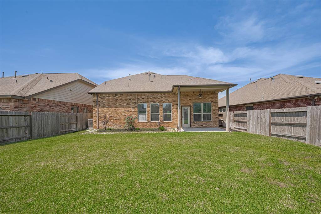 From the far end of the backyard, take in the home’s rear elevation—an inviting backdrop for any outdoor setup.