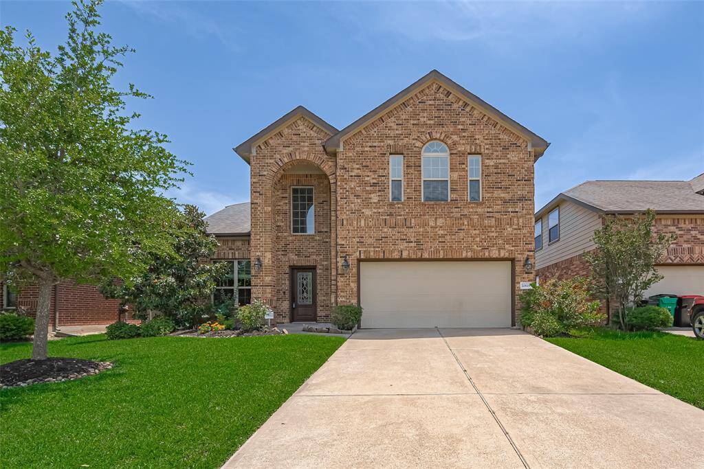 By day, the home’s brick exterior shines bright. A smooth driveway leads to the attached two-car garage, flanked by manicured green lawns.