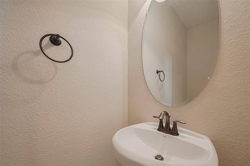 The half bath features a clean aesthetic with a frameless oval mirror and pedestal sink, perfect for guests.