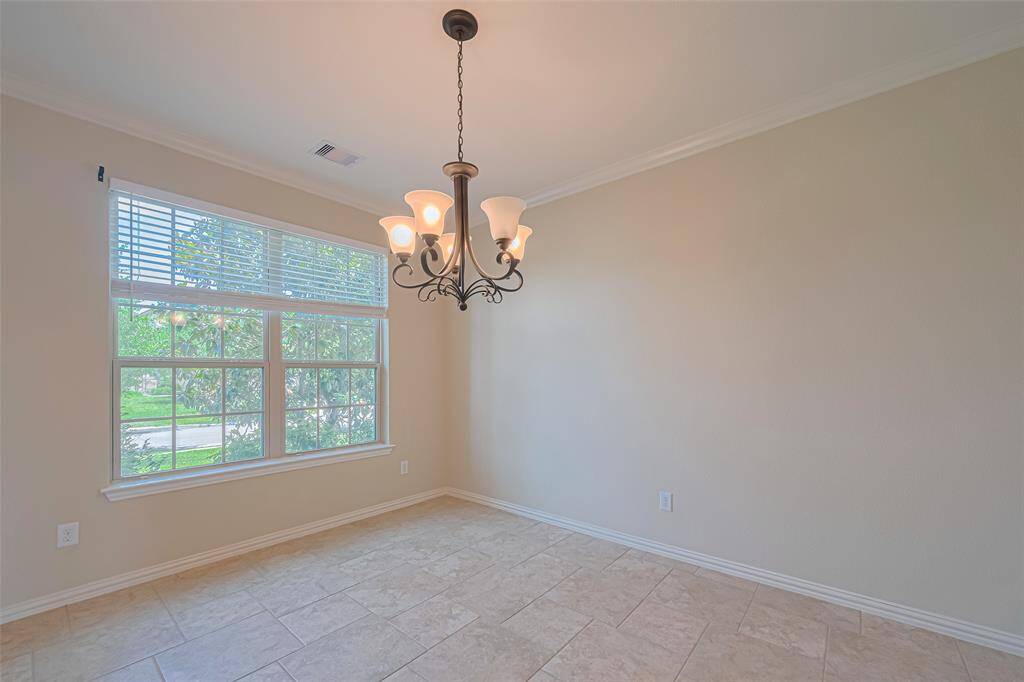 A closer view of the dining room reveals its proportions and thoughtful details, including the crown molding and soft illumination from the central chandelier.