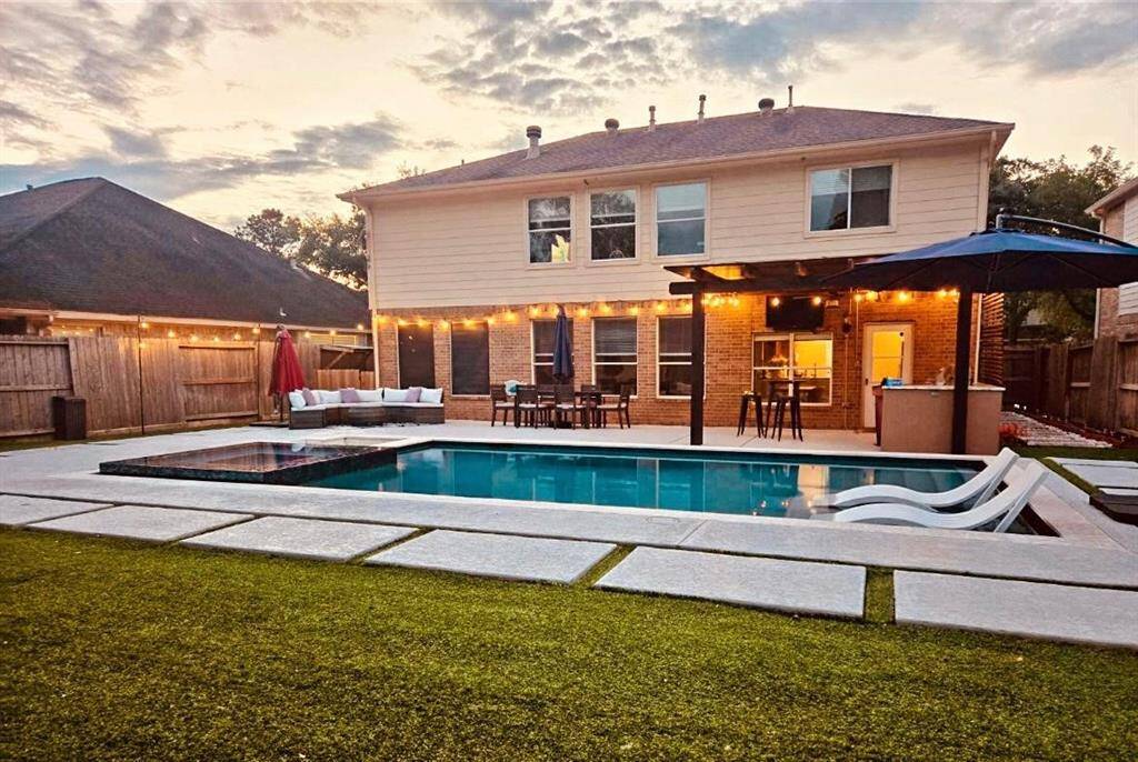 Gorgeous Backyard Paradise with Pergola, Outdoor Kitchen, and a Salt Water Pool with a Tanning Ledge, Fire Pit with Crystal Stones, and a Jetted Hot Tub