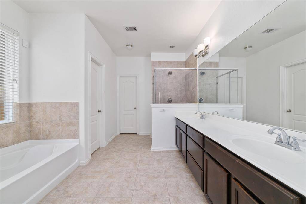Primary bathroom offers tub, shower and double vanity for convenient and relaxation.