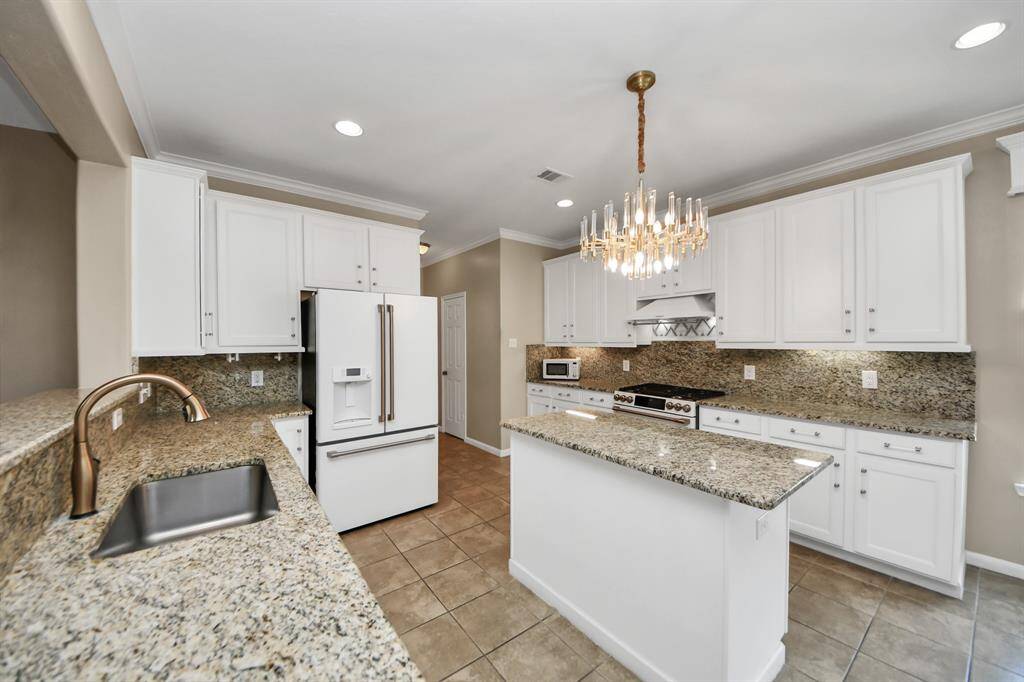 This state-of-the-art kitchen boasts CAFE appliances, a touchless faucet, elegant chandelier and stylish tile flooring.