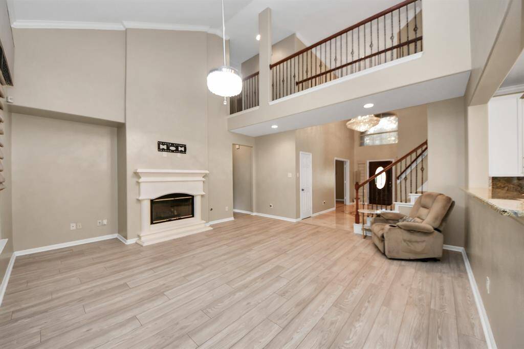A grand, open-concept living space with soaring ceilings and a seamless connection to the upstairs area.