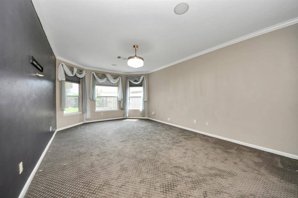 The primary bedroom is a spacious, carpeted retreat designed for comfort and relaxation. Its generous layout allows for a cozy sitting area and more. Large windows flood the space with natural light, creating a bright and inviting atmosphere that enhances its serene ambiance.