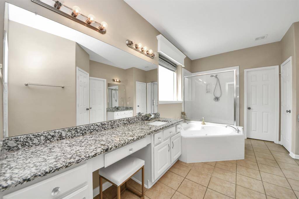 This elegant bathroom features a beautifully crafted granite countertop and a matching vanity that exudes warmth and sophistication.