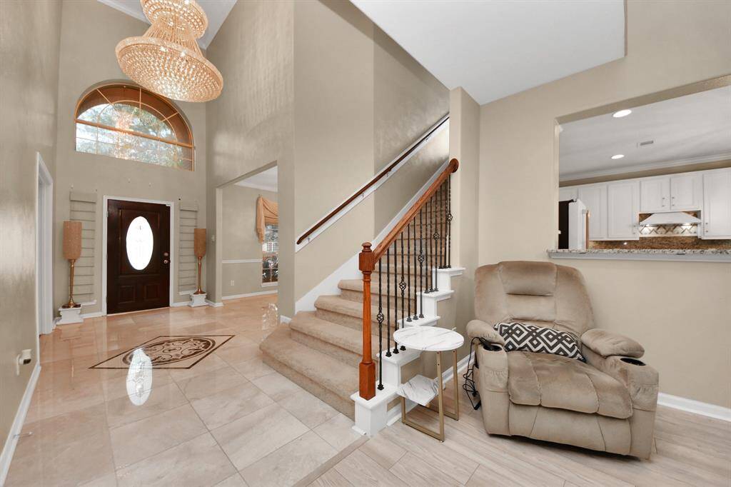 The high ceilings and gracefully ascending staircase create a sense of openness, while the foyer offers a refined space for relaxation or conversation.