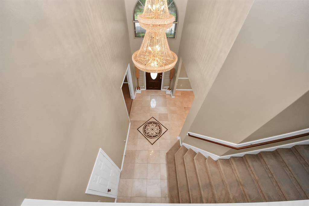 From the upstairs vantage point, the towering chandelier, adorned with crystals and the Italian Marble flooring, commands attention with its dramatic presence.
