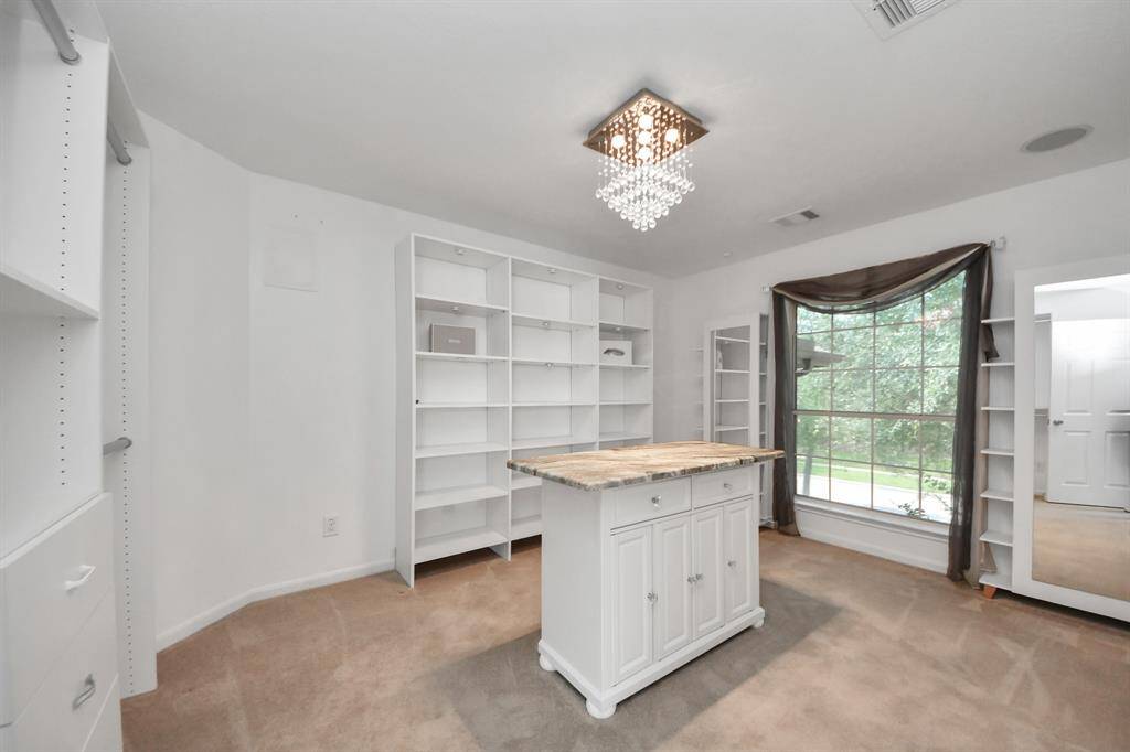 This is a bedroom converted in a large walk-in closet! Elegant decoration elements like the light fixture, add a touch of sophistication to this CALIFORNIA closet, while a gracefully decorated window introduces architectural charm, making the space both inviting and visually distinctive.