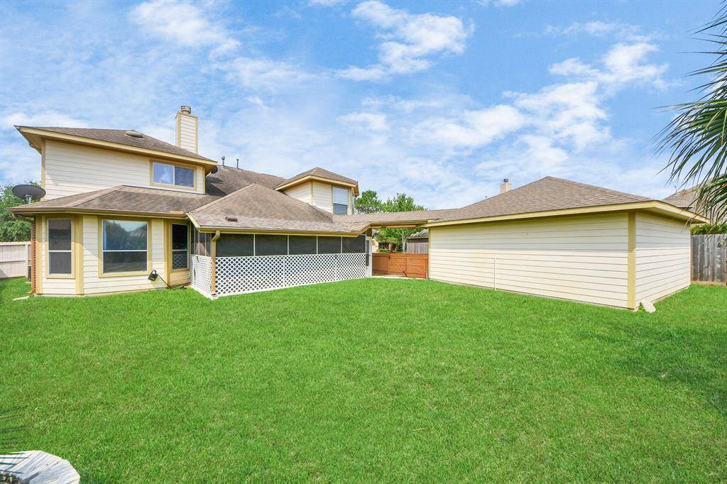 The home's backyard showcases a beautifully landscaped, fenced area, where lush greenery and neatly trimmed grass create a serene outdoor retreat.