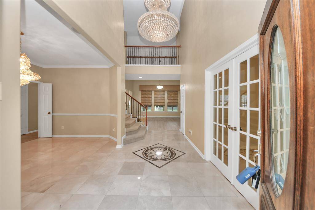 Enter a grand foyer where soaring ceilings and a graceful chandelier make a breathtaking first impression—an ideal setting to welcome guests with elegance and style.
