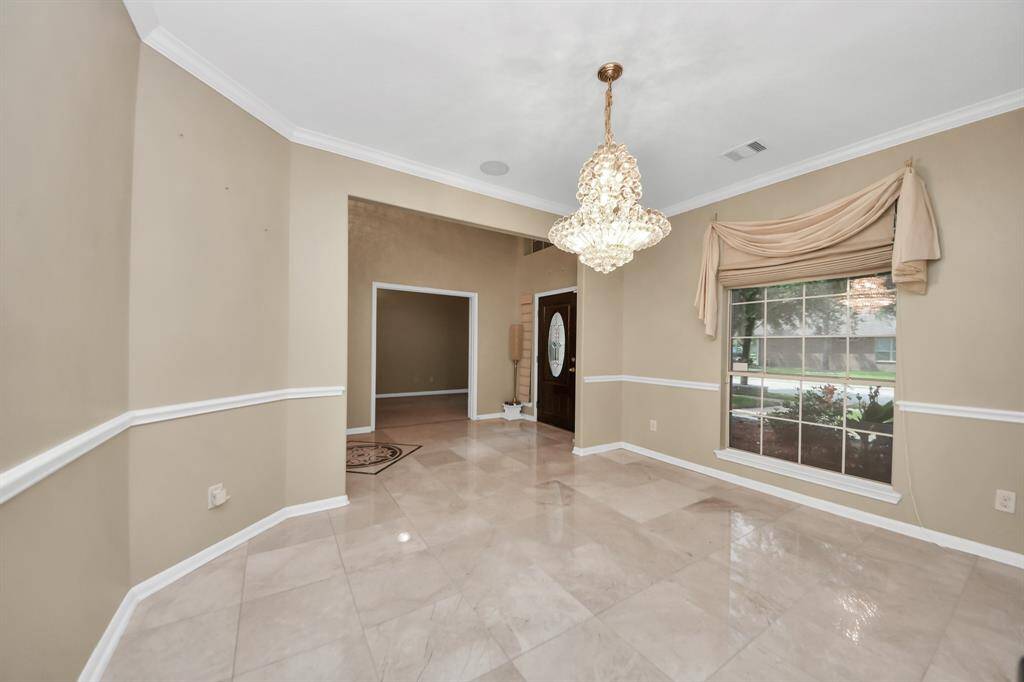 Sunlight streams through the expansive glass-paneled window, and with the chandelier together illuminate the space with a warm, inviting glow.