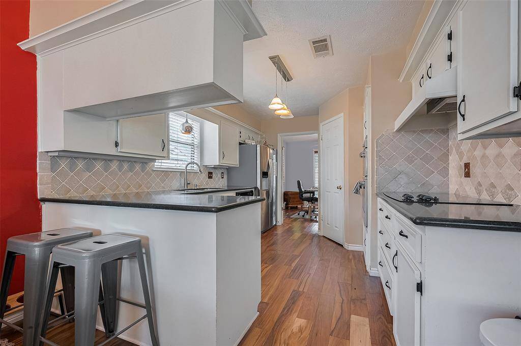 Charming galley-style kitchen with crisp white cabinetry, breakfast bar seating, and cheerful natural light—perfect for everyday meals or morning coffee chats.