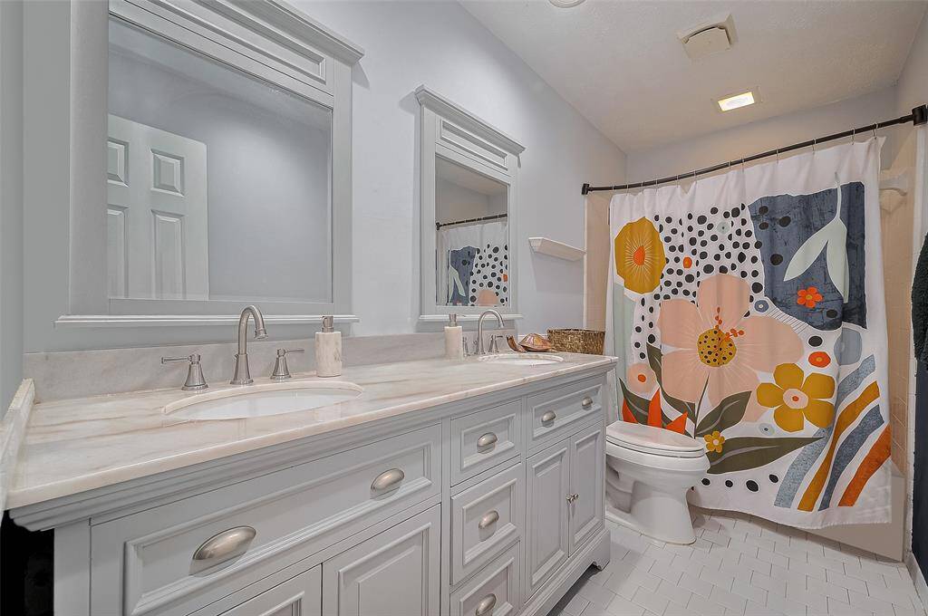 Bright and cheery full bath with double vanity, modern fixtures, and playful pops of color—perfect for guests or a shared family space.