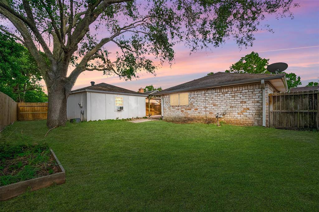 Expansive backyard with towering shade tree and garage—great potential for a workshop, studio, or extra storage.