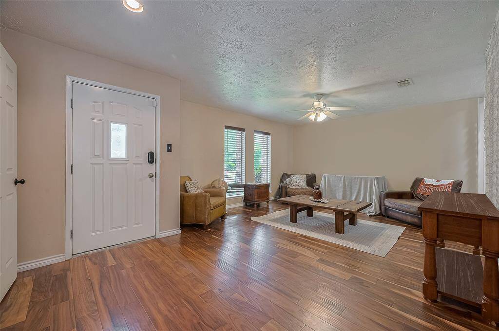 Warm and spacious living area with rich wood flooring, natural light from large windows, and a neutral palette ready for your personal touch—perfect for gathering or relaxing.