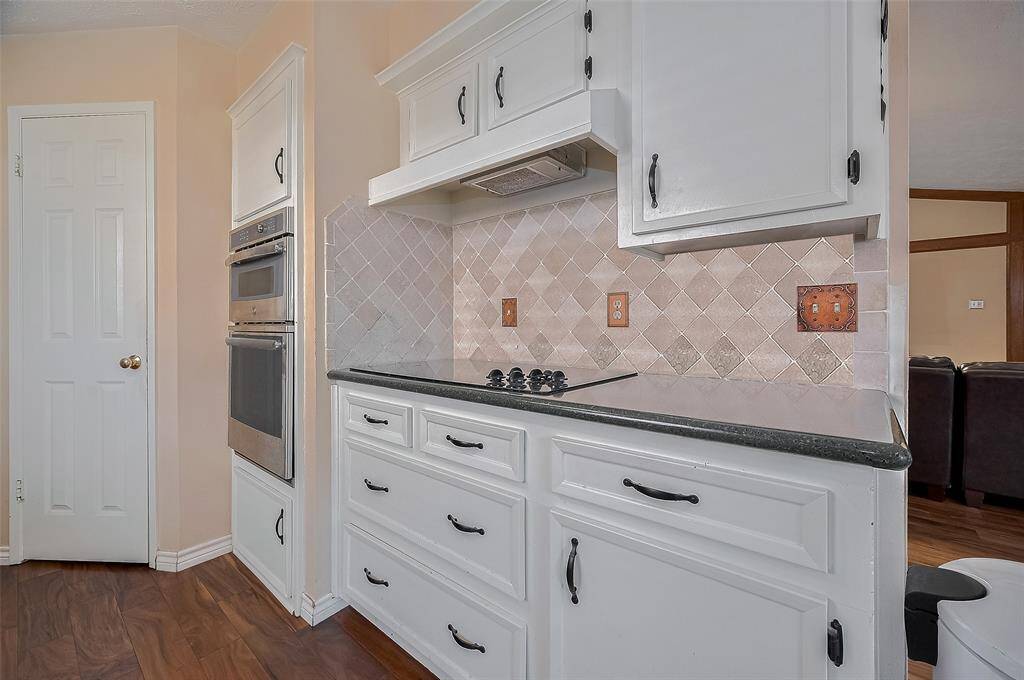 Sleek cooktop and double ovens nestled in a classic tile backsplash offer both functionality and style for home chefs.