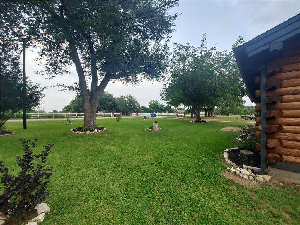 This photo showcases a spacious, well-maintained lawn with mature trees and a charming log cabin exterior. The property is offering a picturesque and serene setting ideal for outdoor activities and relaxation.
