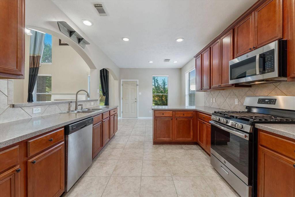 Another view of the kitchen with rich wood cabinetry and Corian counters.