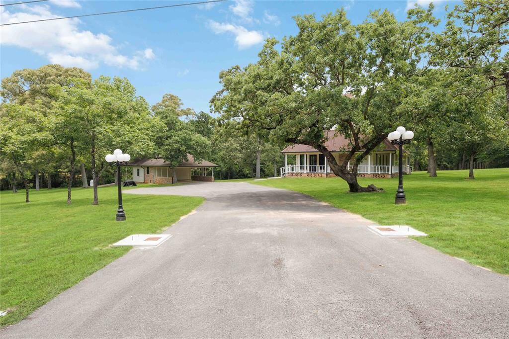 A private drive framed with trees and outdoor lighting leads the way to your new home.
