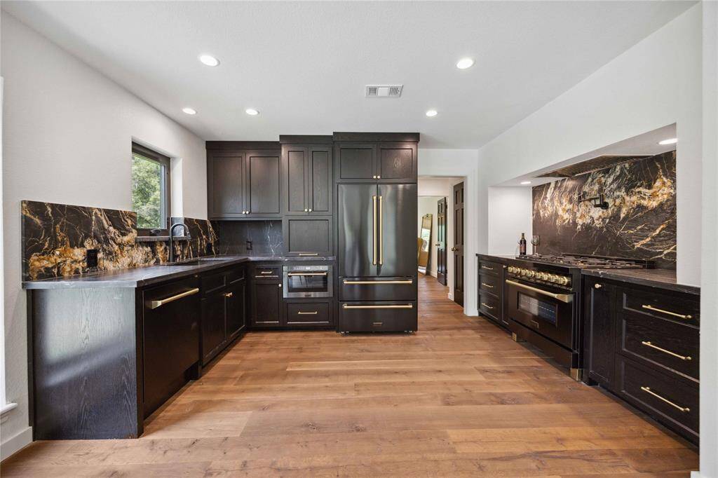 The open floor plan seamlessly connects the living room to this outstanding custom kitchen! Featuring custom white oak cabinets with a sleek black onyx stain, you'll have plenty of space to store dishes and small appliances.