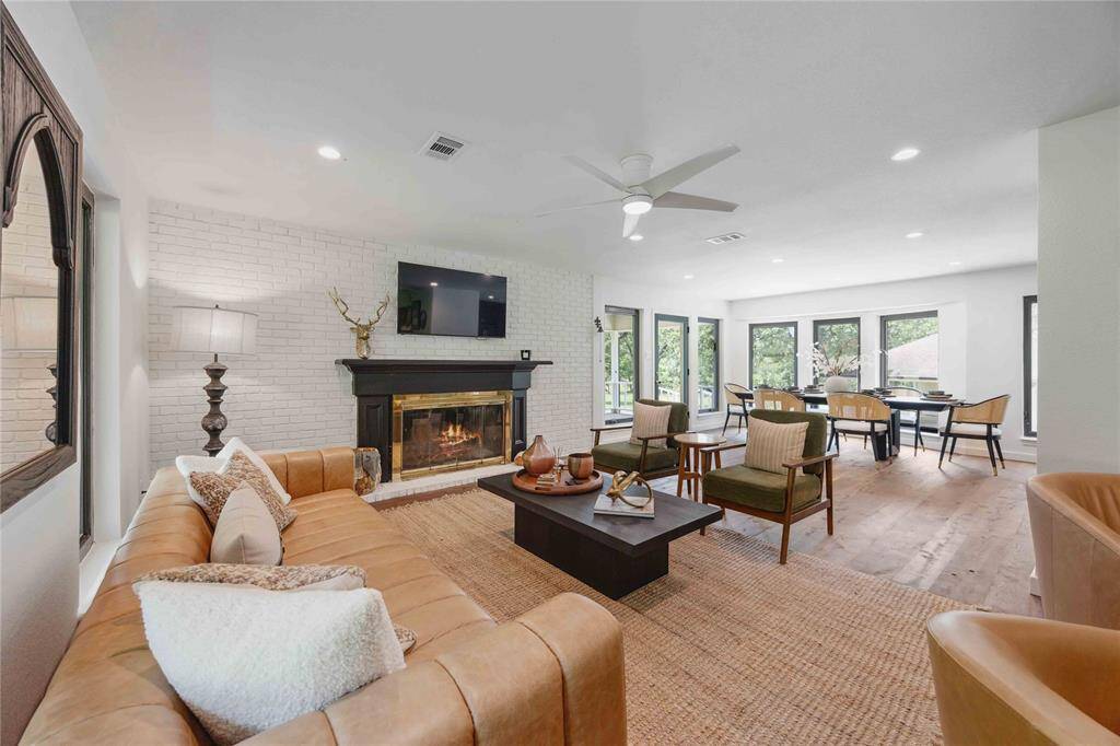 The living room features a central gas log fireplace, perfect for a relaxing evening. The room opens to a lovely dining room surrounded by perfectly framed picture windows.
