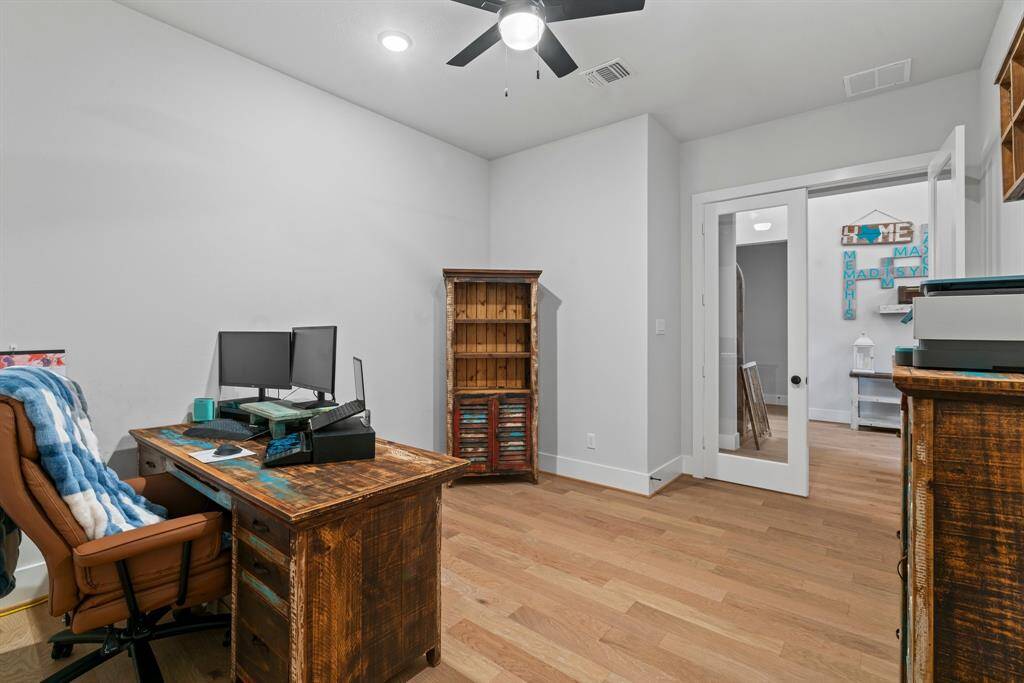 Dedicated home office with french doors with glass panes and warm wood flooring—ideal for remote work.
