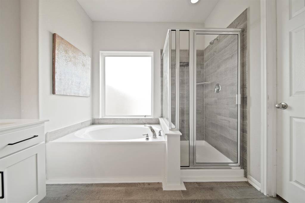 Complete with dual sinks, a large mirror, wooden cabinetry, and tile floors.