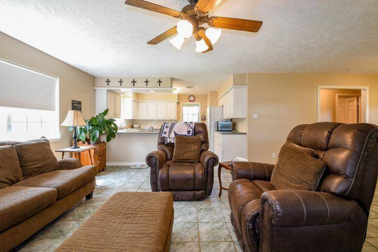 A bar separates the fully equipped kitchen and living area with plenty of natural light with multiple windows.