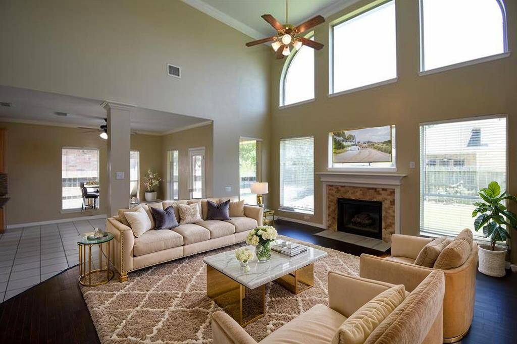 This dining area features large windows with ample natural light, a stylish chandelier, and dark wood flooring.