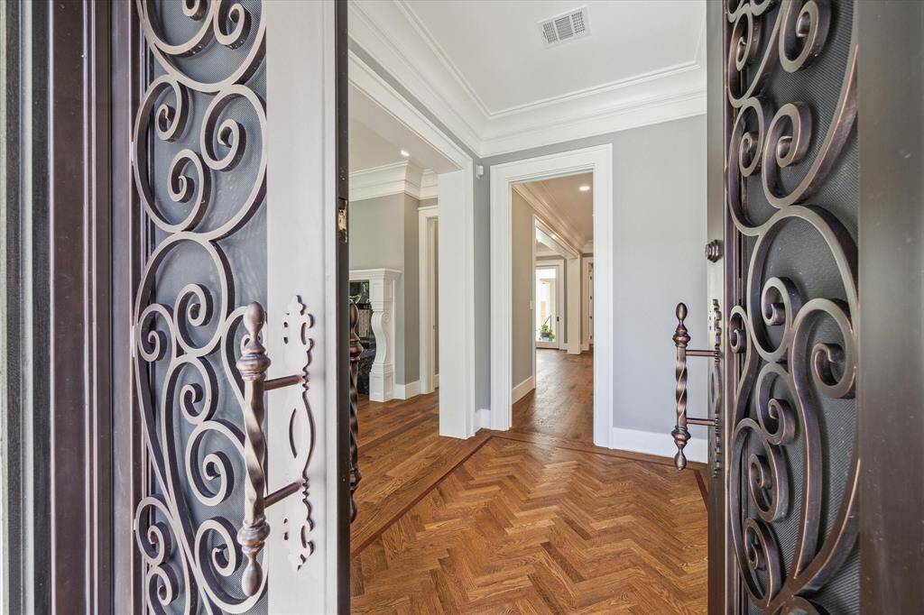 Imagine bringing your friends through these beautiful iron doors onto the herringbone wood flooring in the entry and on into your new home!