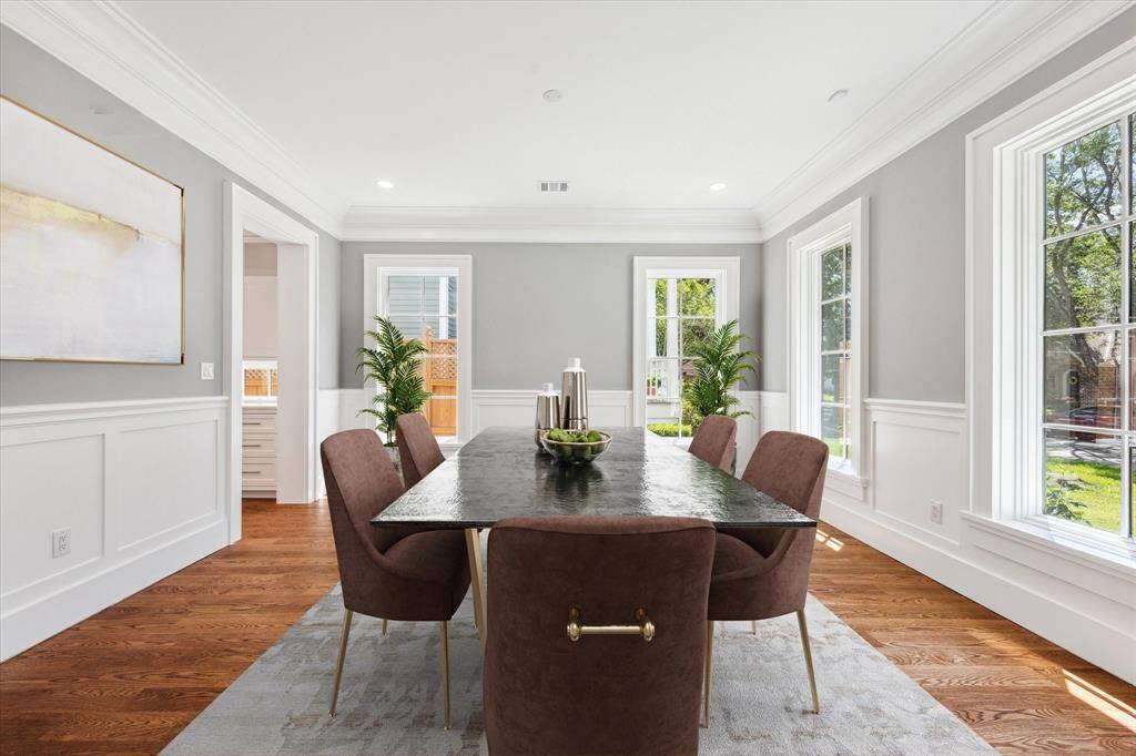 The light filled formal dining room has custom designed wainscotting and crown molding, high ceilings, beautiful hardwood floors and four full length windows! This is the ideal place for family dinners or festive parties! This photo has been virtually staged.