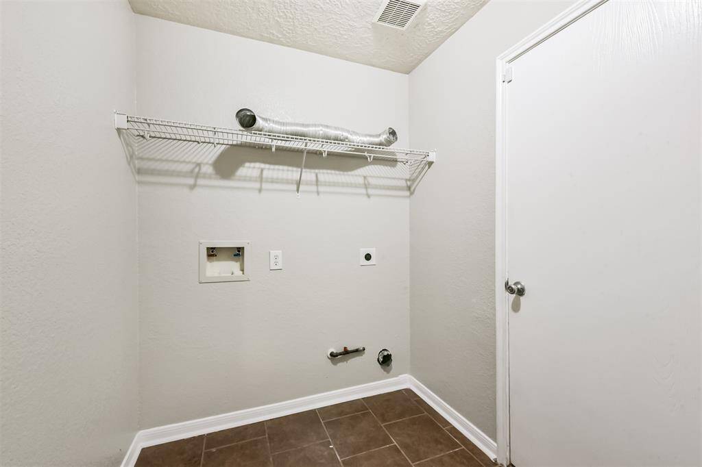 Spacious laundry room with convenient hookups and shelving, perfect for efficient organization.