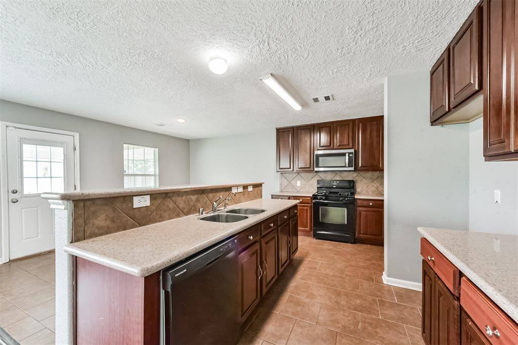 Kitchen with black appliances and corian countertops.