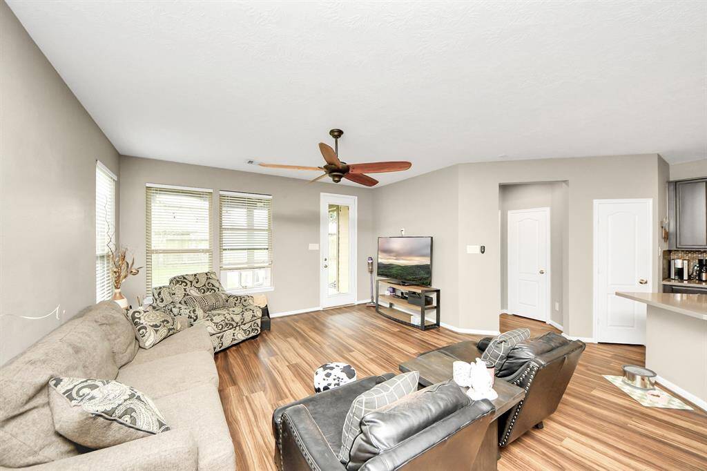 The living room features a dark stainedceiling fan, gorgeous floors, andlarge windows that provide plenty ofnatural lighting throughout the day.