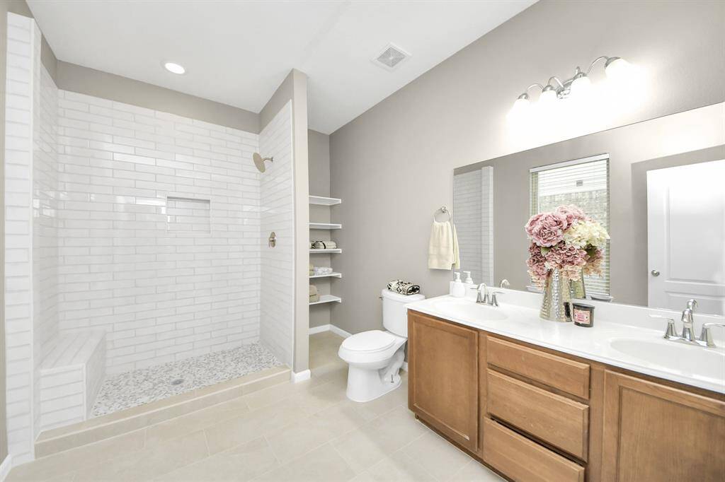 The primary bathroom features tilefloors, wood cabinets, beautifulcountertops, walk-in shower with tile seat, and dual sinks!