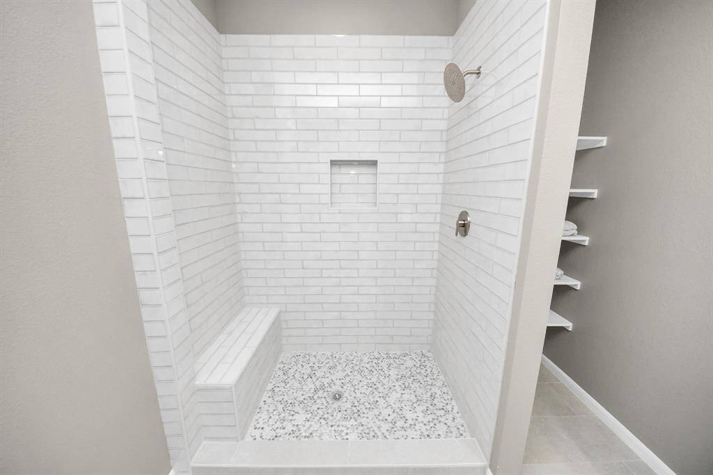 The primary bathroom features tilefloors, wood cabinets, beautifulcountertops, walk-in shower with tile seat, and dual sinks!