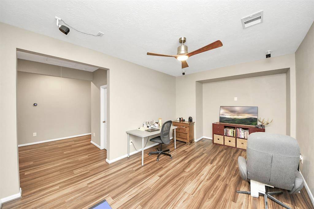 The handsome homeoffice features beautiful flooring and a ceiling fan.