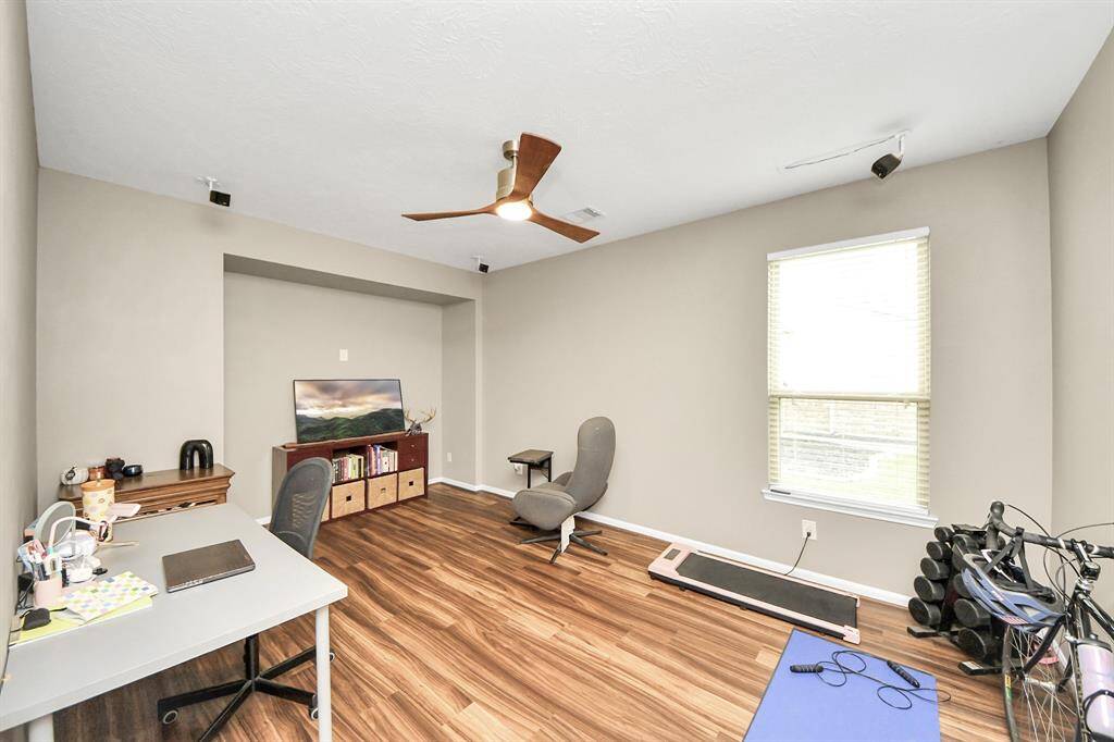 The handsome homeoffice features beautiful flooring and a ceiling fan.