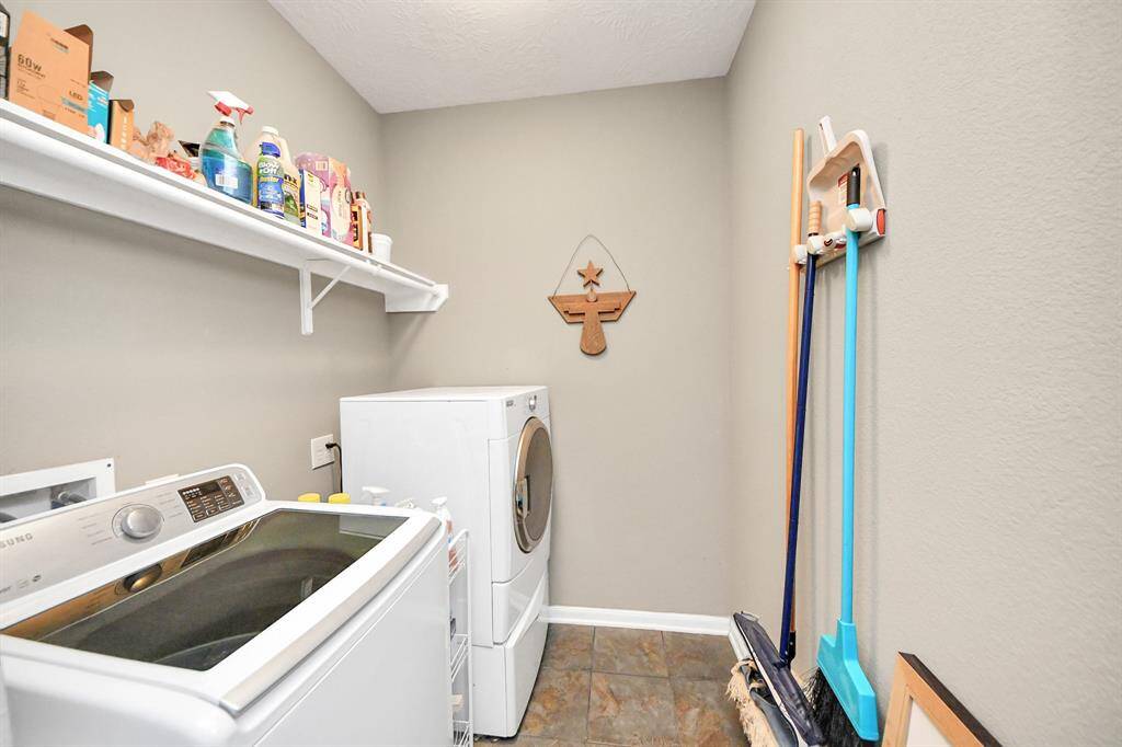 The laundry room featuresconnections for a washer, dryer, tile floors, and storage space.