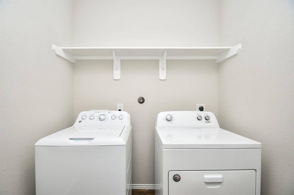 The utility room easily accommodates dual laundry appliances, with handy storage, above.