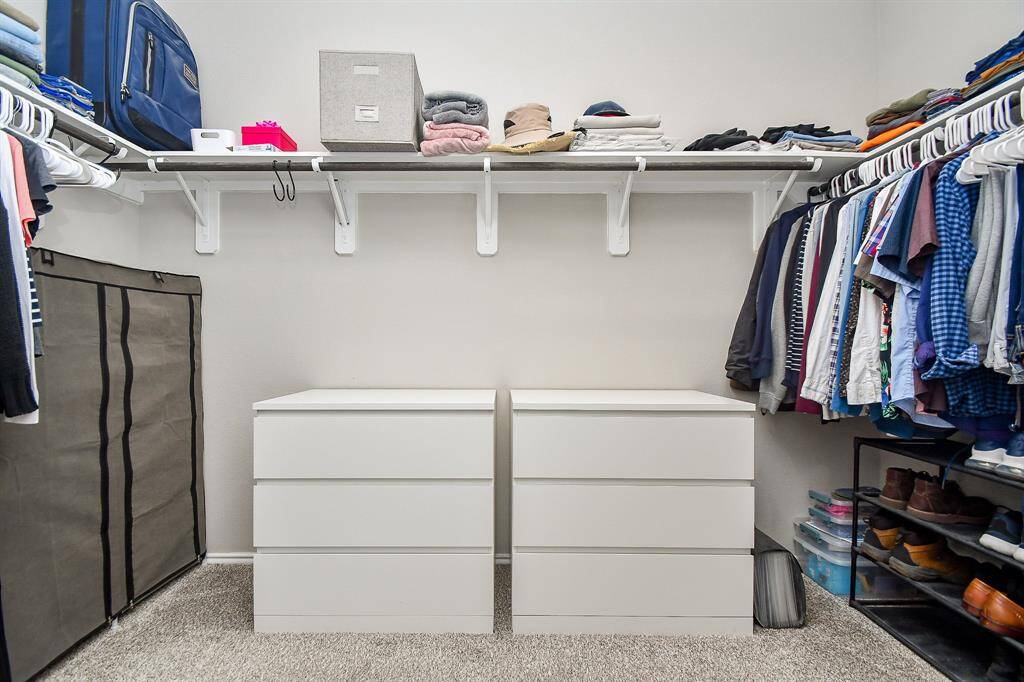 This exceptional primary carpeted walk-in closet will store and organize just about everything you own in one convenient, luxurious space.