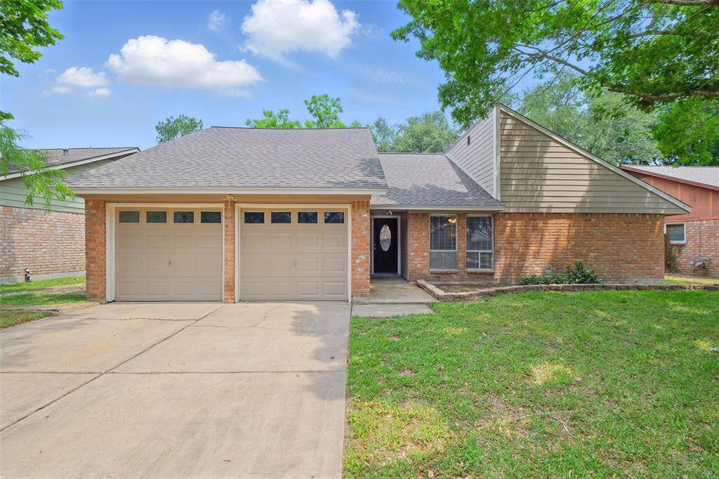 This charming home features a classic brick exterior with a two-car garage and mature trees providing ample shade. The recently refinished front door is inviting with it's leaded glass detail.