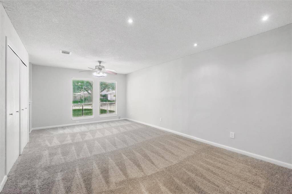 Spacious primary bedroom featuring an updated ceiling fan, recessed lighting and fresh paint.
