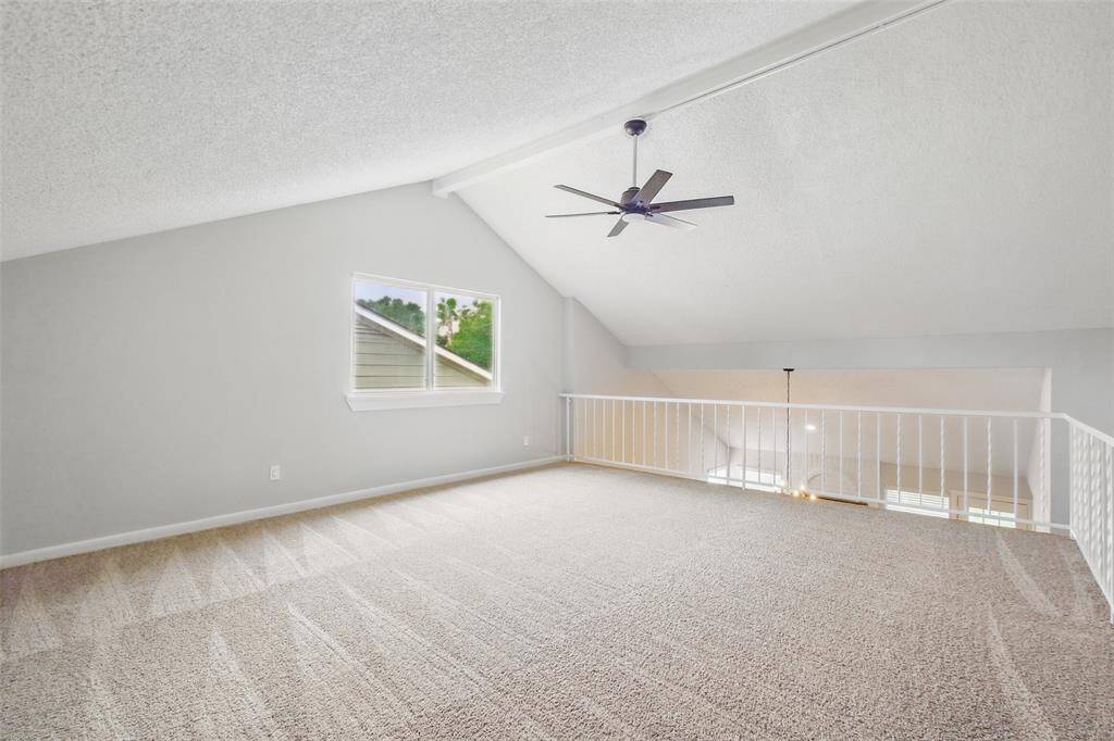 The upstairs game room is large featuring an updated ceiling fan, iron spindles, a vaulted ceiling and storage closet.