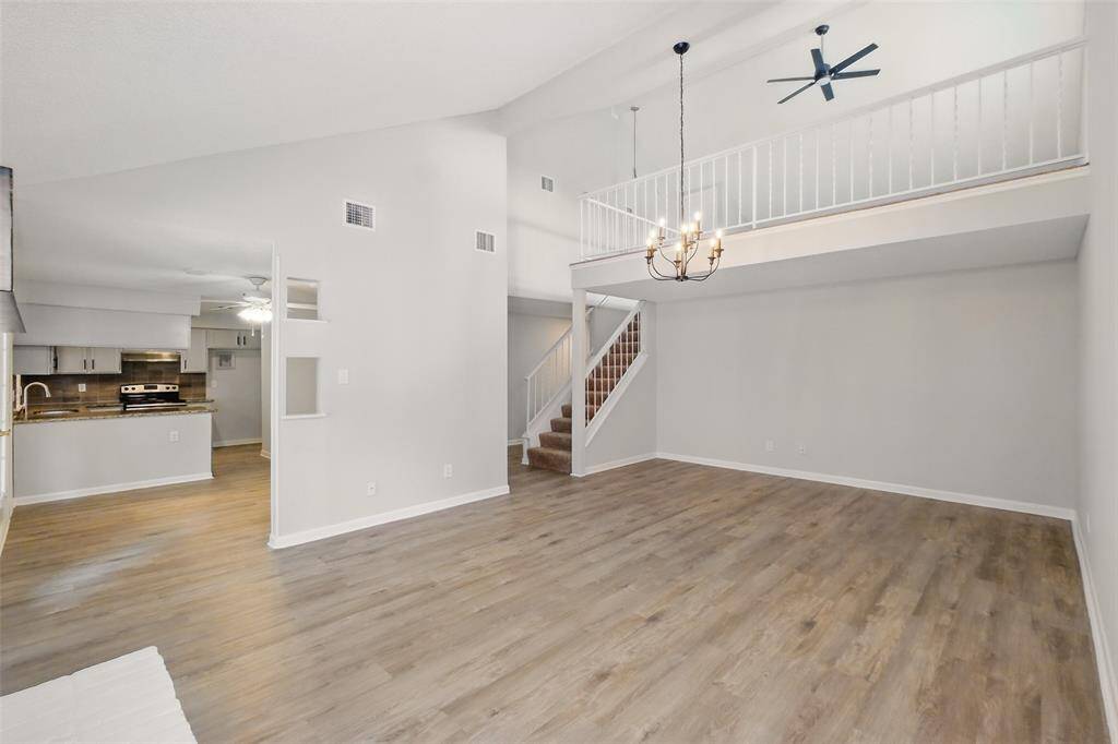 This photo showcases a spacious, open-plan living area and a game room accessible by stairs.
