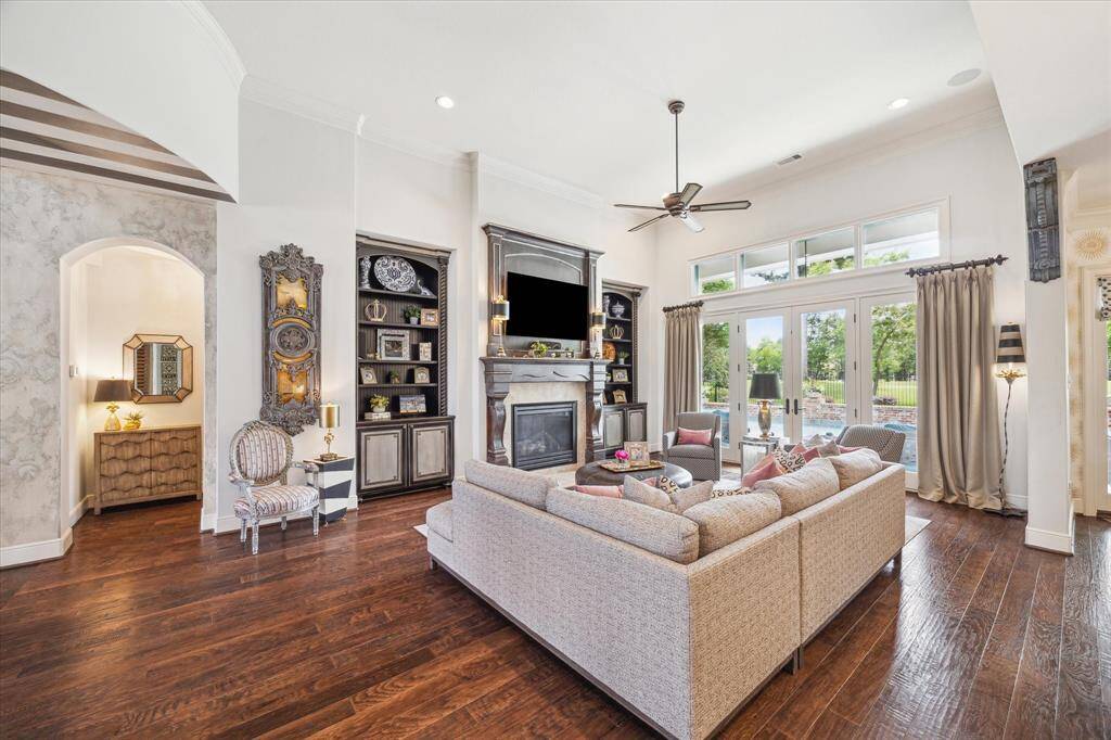 The main living area enjoys the warmth of the stone clad fireplace and a generous wall of windows, transoms and French doors which allow natural light to stream in and provide an unobstructed panoramic view of the patio, pool and golf course.