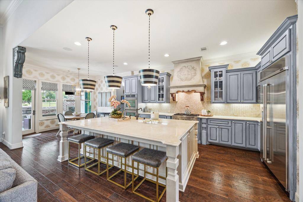 This dreamy kitchen features abundant storage and display cabinetry in a rich, French blue hue reflective of the entire home's timeless elegance. The furniture-style kitchen island is a beautiful focal point boasting custom details to mimic the antique accents throughout the house, creating a cohesive and stylish look. The island allows for both seating and storage.